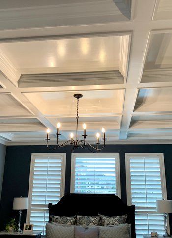 A bedroom with a chandelier hanging from the ceiling and a bed.