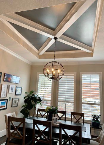 A dining room with a table and chairs and a chandelier hanging from the ceiling.