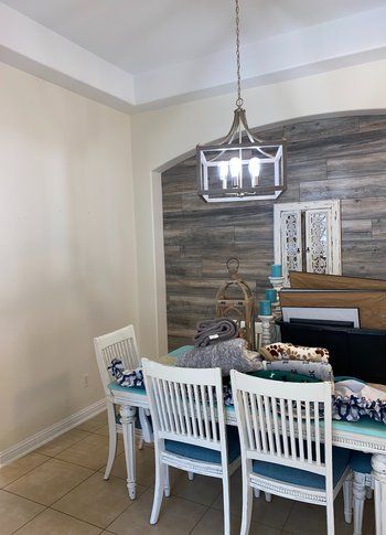 A dining room with a table and chairs and a chandelier hanging from the ceiling.