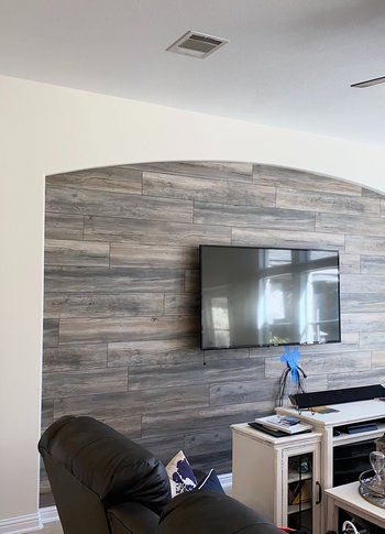A living room with a wooden wall and a flat screen tv.