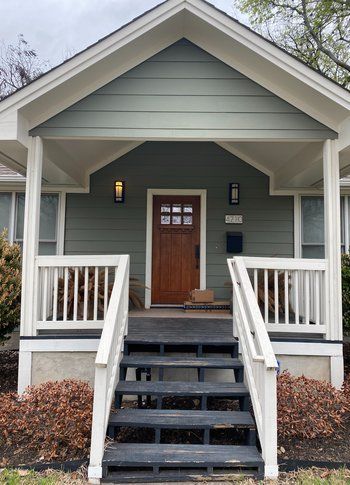 A house with a porch and stairs leading to the front door.