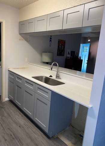 A kitchen with a sink , cabinets and counter tops.