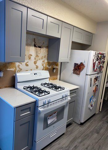 A kitchen with a stove , refrigerator , and cabinets.