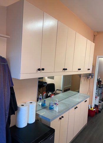 A kitchen with white cabinets and a large mirror.