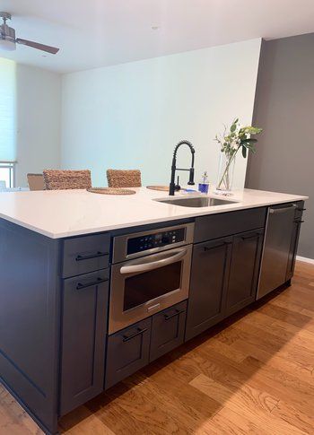 A kitchen with a large island , sink , oven and dishwasher.