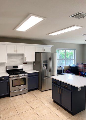 A kitchen with stainless steel appliances and blue cabinets.