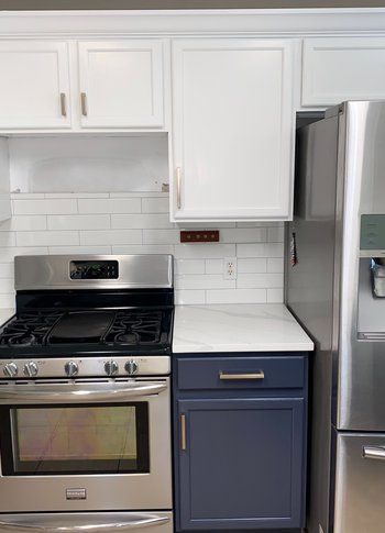 A kitchen with a stove , oven , refrigerator and white cabinets.
