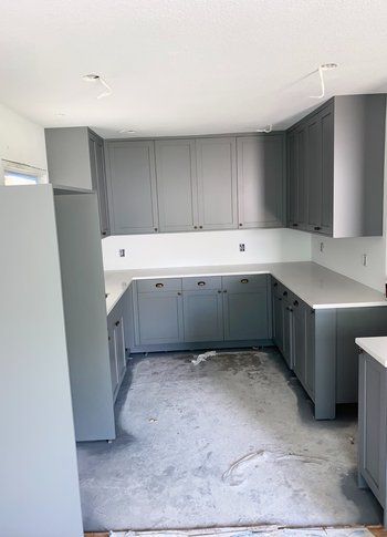 A kitchen with gray cabinets and white counter tops is being remodeled.