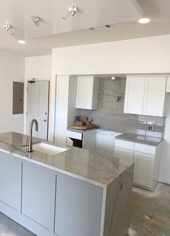 A kitchen with white cabinets , granite counter tops , and a sink.