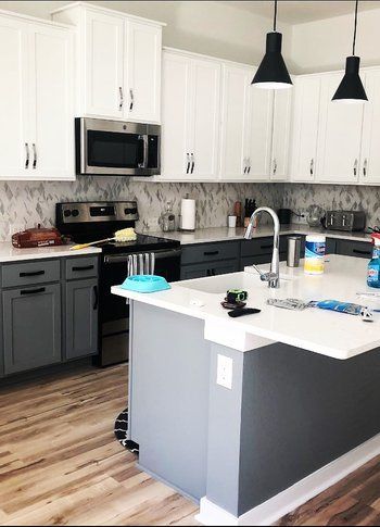 A kitchen with gray cabinets and white counter tops