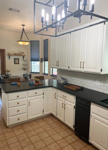 A kitchen with white cabinets and black counter tops.