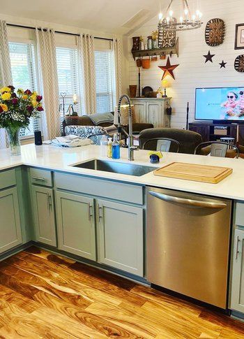 A kitchen with a sink , dishwasher , and television.