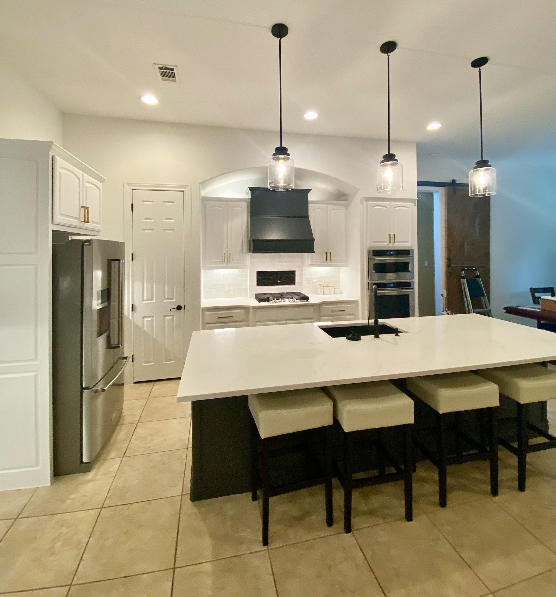 Austin kitchen remodel in Brushy Creek with custom vent hood painted cabinets quartz countertops and tile backsplash niche