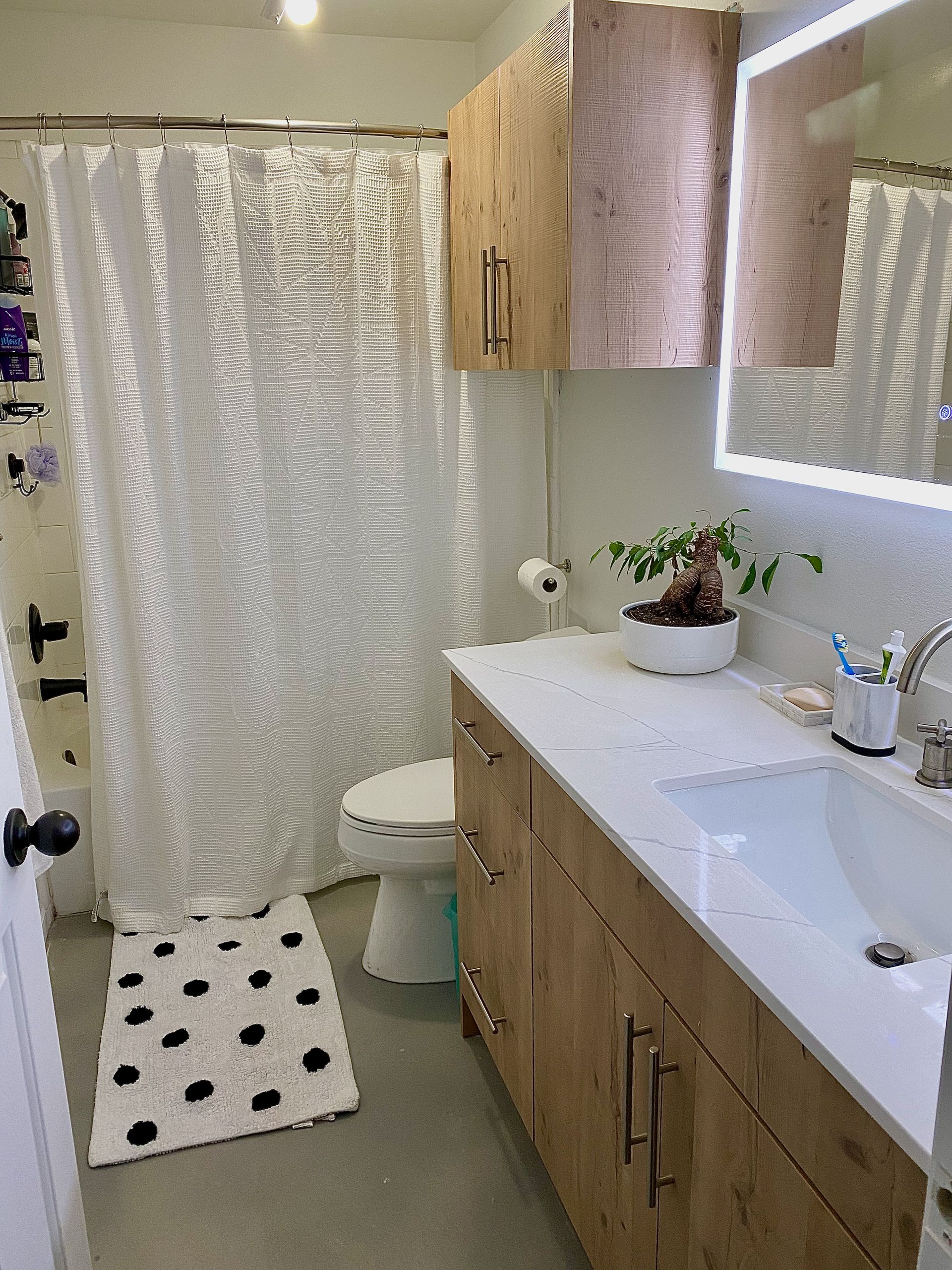 Guest bathroom remodel in Dripping Springs featuring European style Rustic Oak frameless cabinets and Calacatta Ultra quartz completed by Austin Painting and Cabinets