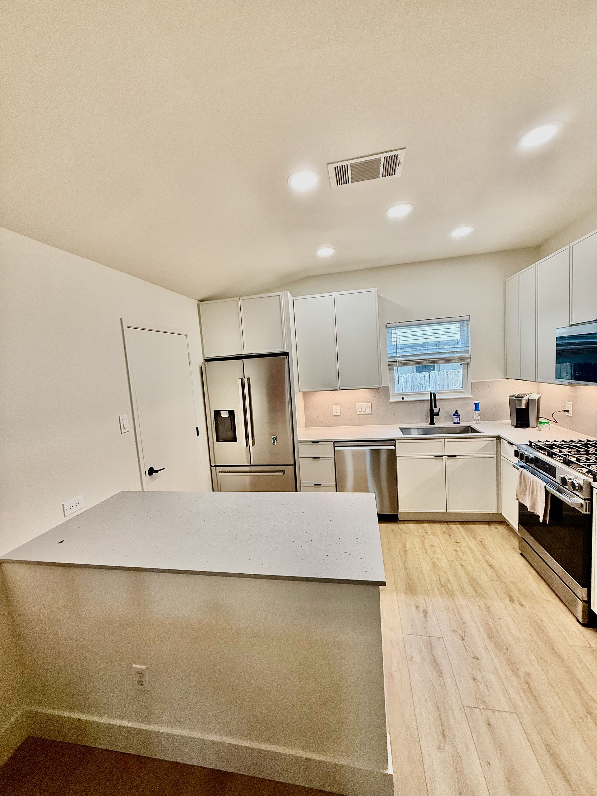 Remodeled Northwest Austin kitchen with slim shaker cabinetry undercabinet lighting and luxury vinyl flooring