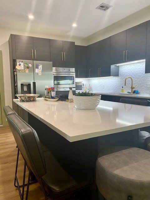 A kitchen with a large island , stools and a refrigerator.