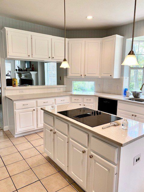 A kitchen with white cabinets and a large island