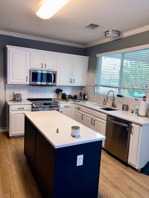 A kitchen with white cabinets and stainless steel appliances