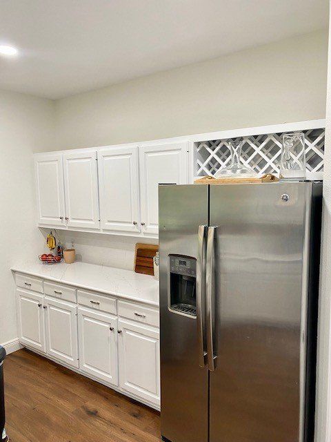 A kitchen with white cabinets and a stainless steel refrigerator.