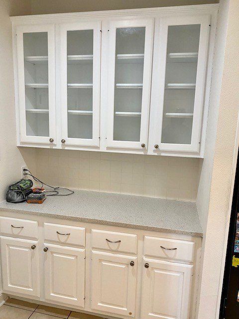 A kitchen with white cabinets and glass doors