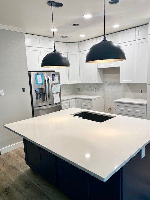 A kitchen with white cabinets and a large island in the middle.