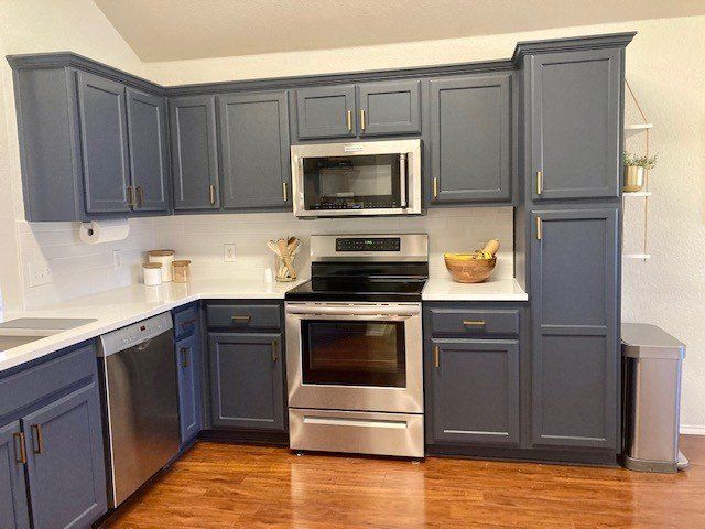 A kitchen with blue cabinets and stainless steel appliances.