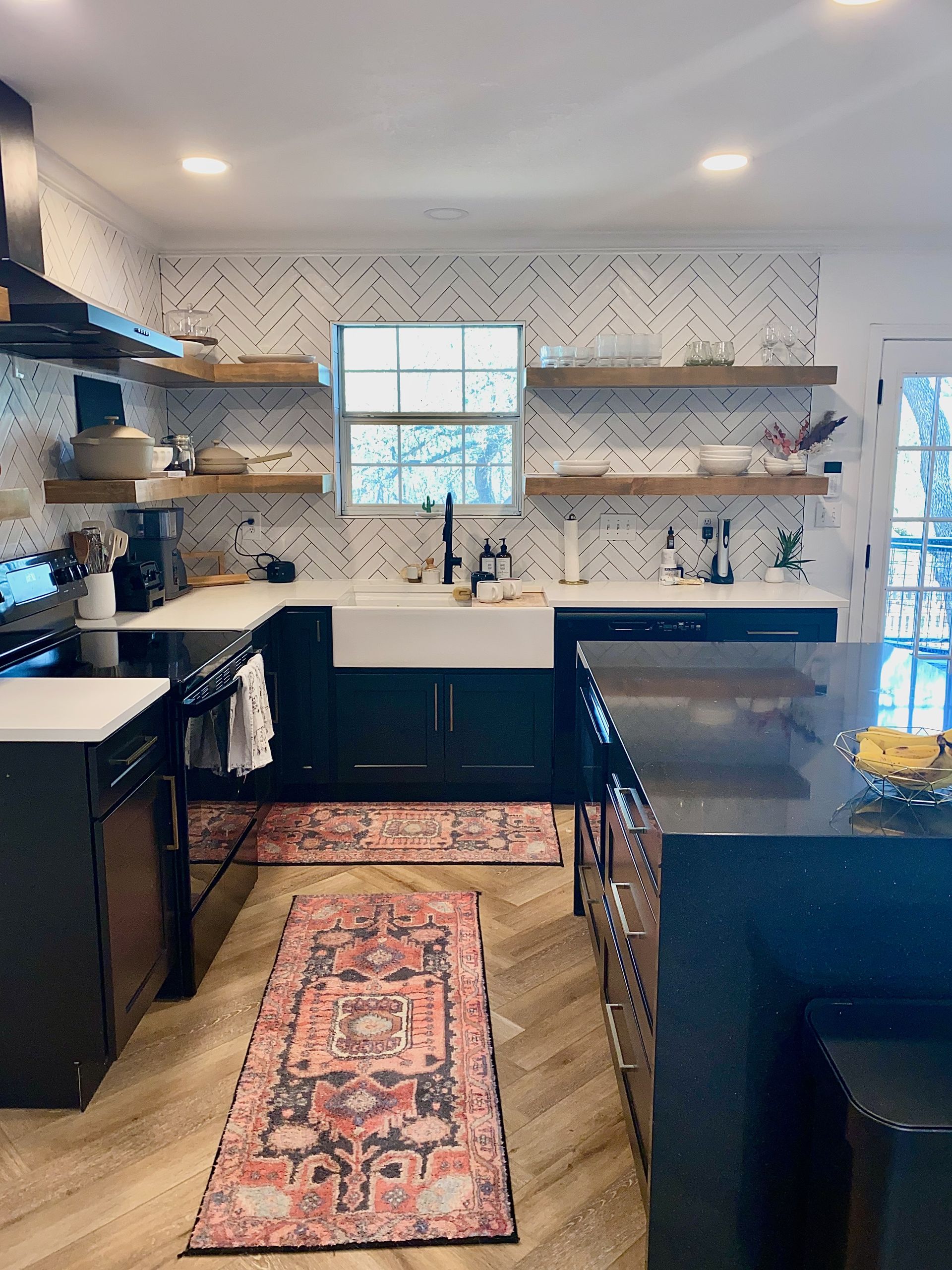 Kitchen remodel in Austin with new shaker cabinets custom painted cabinets quartz countertops waterfall island floating shelves and herringbone tile backsplash