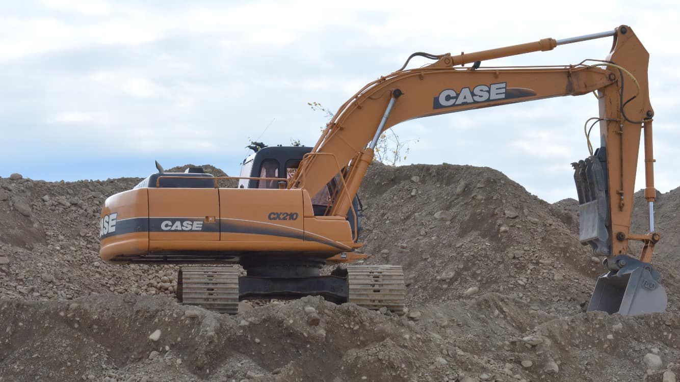 A case excavator is sitting on top of a pile of dirt.