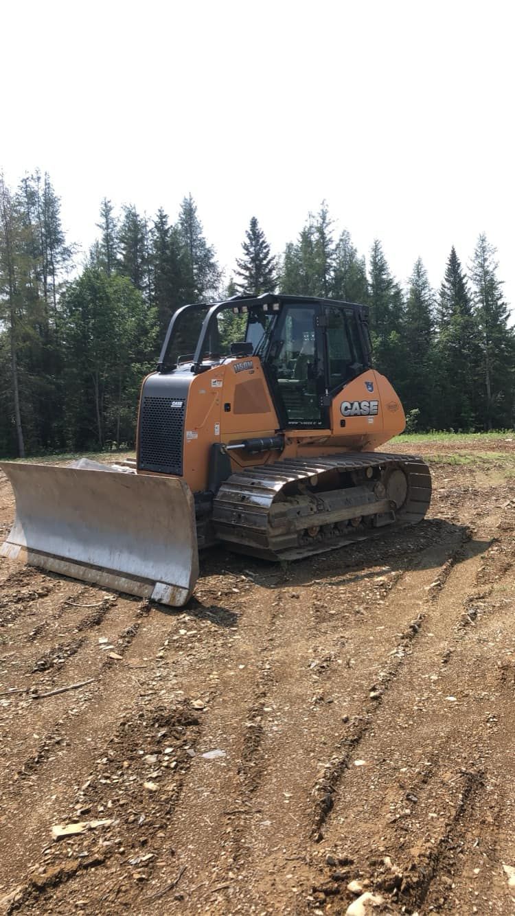 A bulldozer is sitting in the middle of a dirt field.
