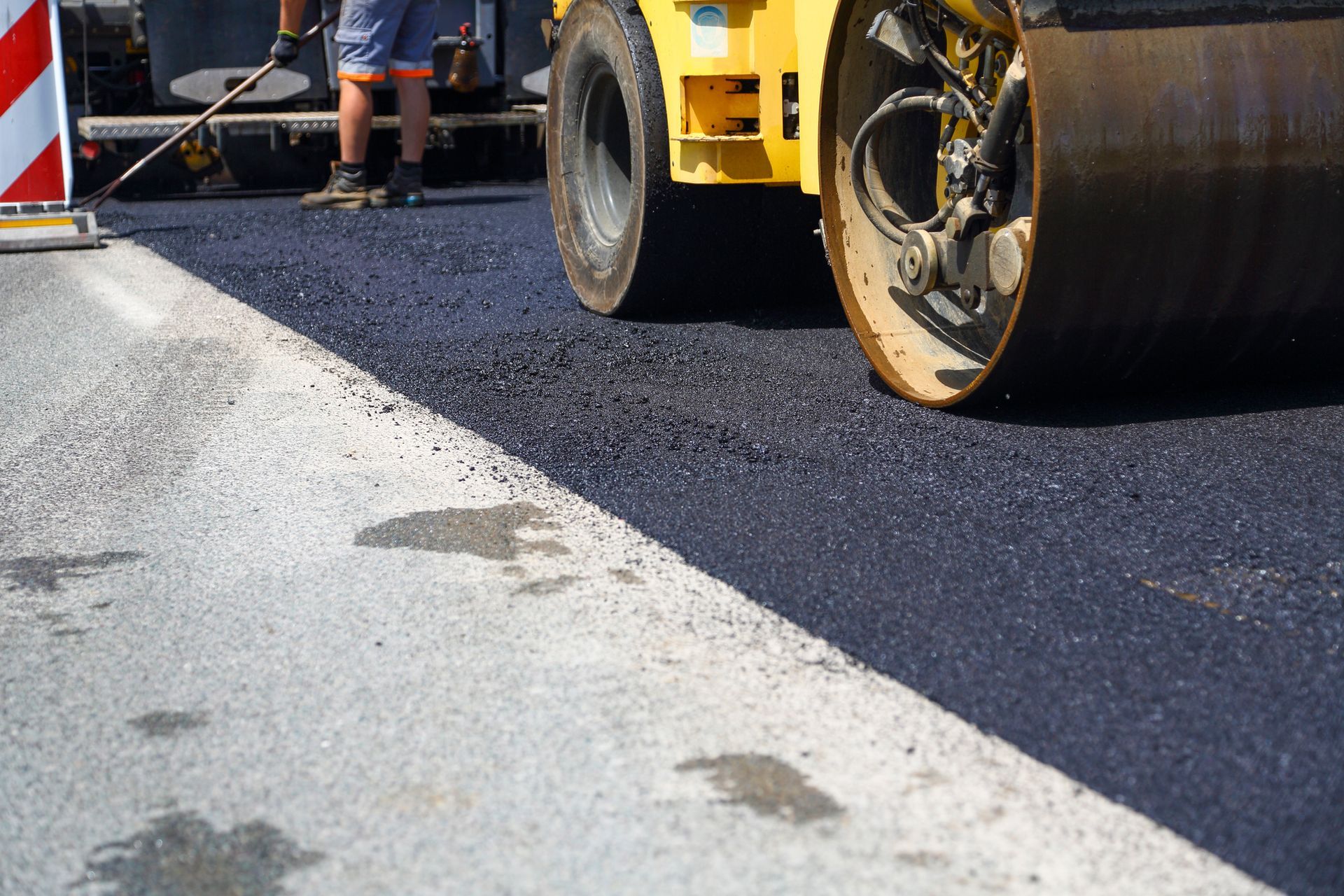 Road roller compacting fresh asphalt on a road.