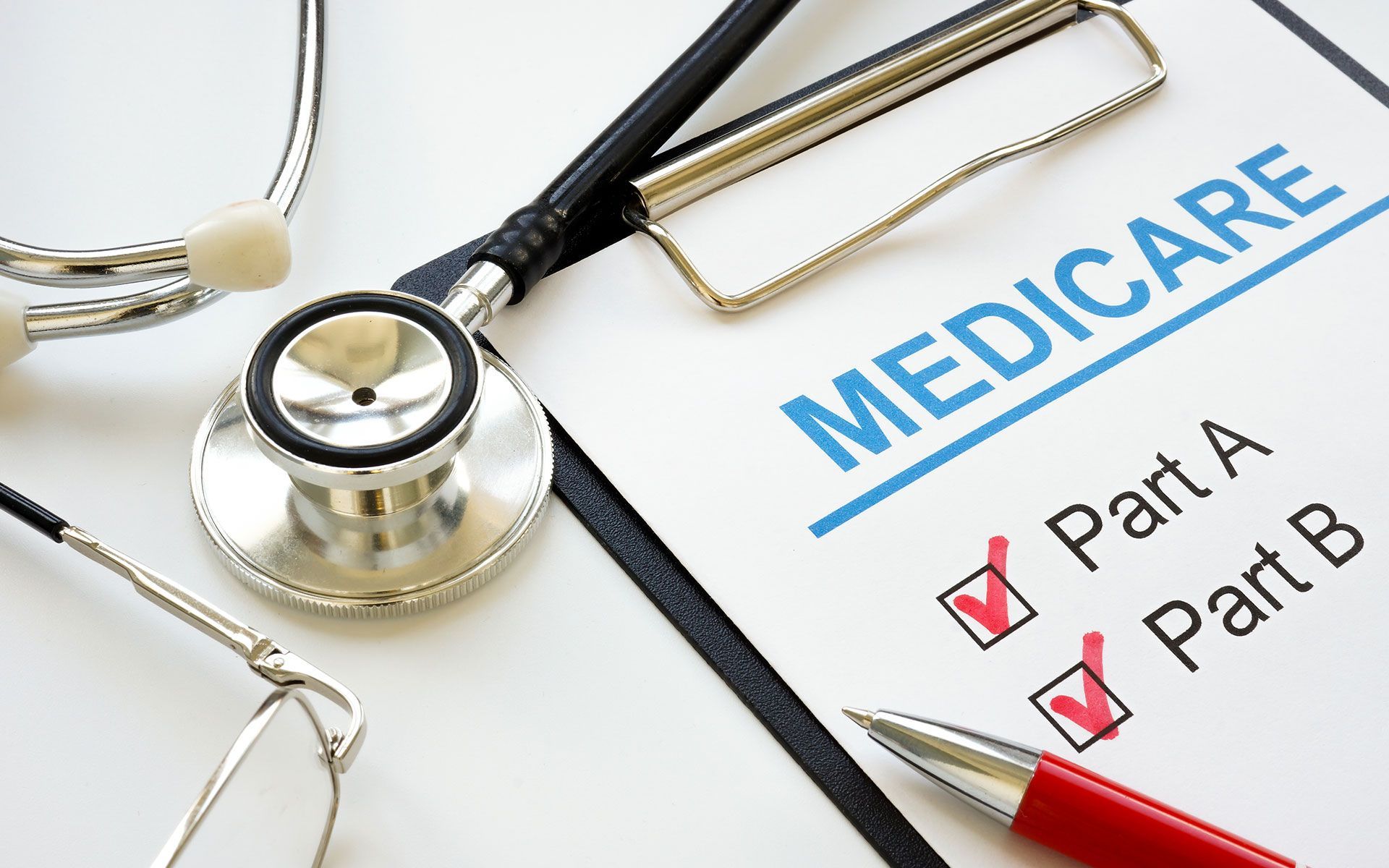 Stethoscope and Medicare form on clipboard, with checkmarks by Part A and Part B.