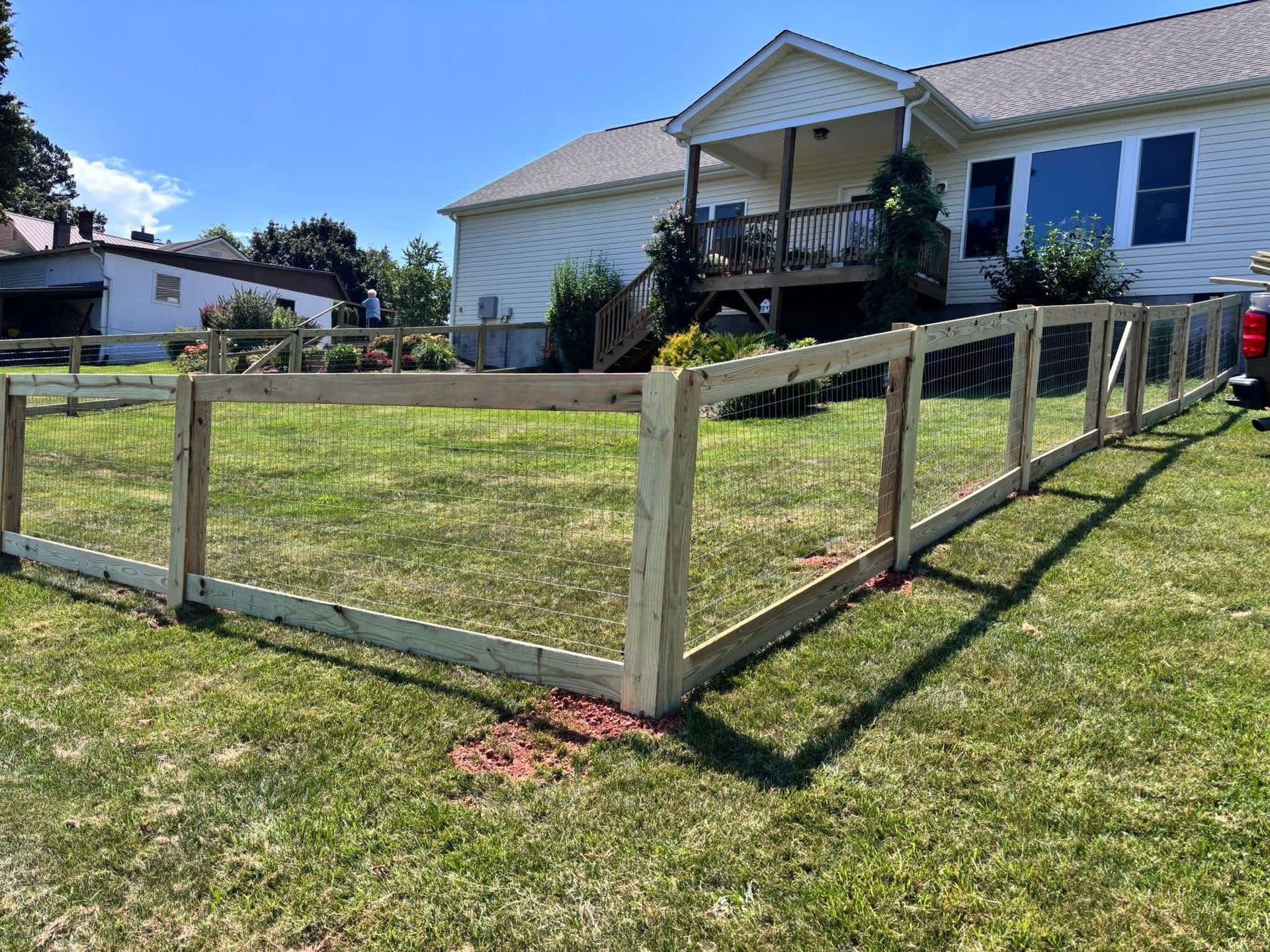 Wooden fenced yard beside a white house on a sunny day