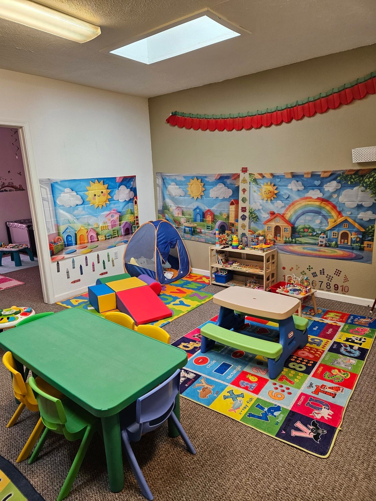 Colorful classroom play area with mats, toy blocks, a blue tunnel, and children’s rugs on the floor