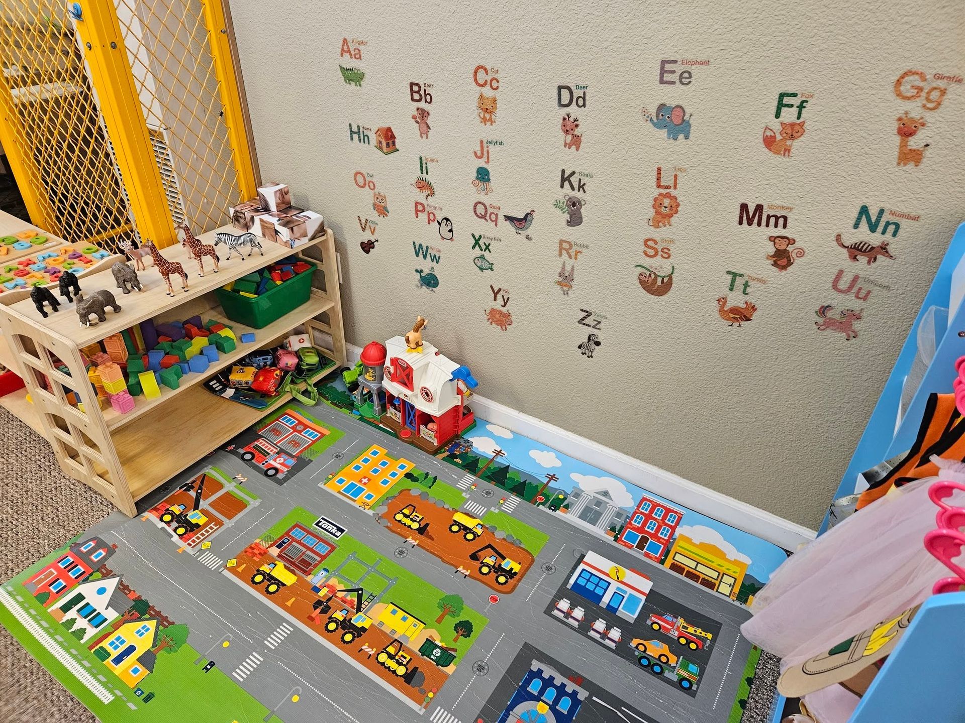 Colorful children’s playroom with alphabet wall decals, toy shelves, and a road-pattern play mat