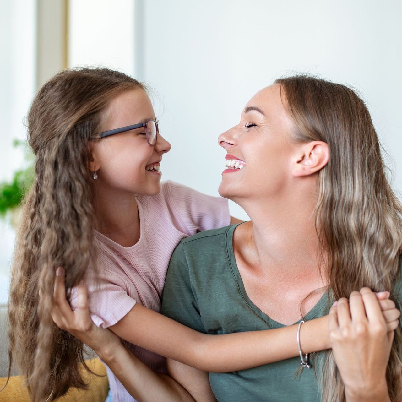 Una mujer y una niña se abrazan y sonríen.