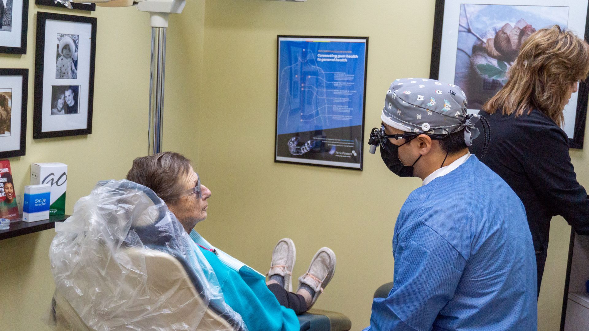 A woman is sitting in a dental chair talking to a dentist.