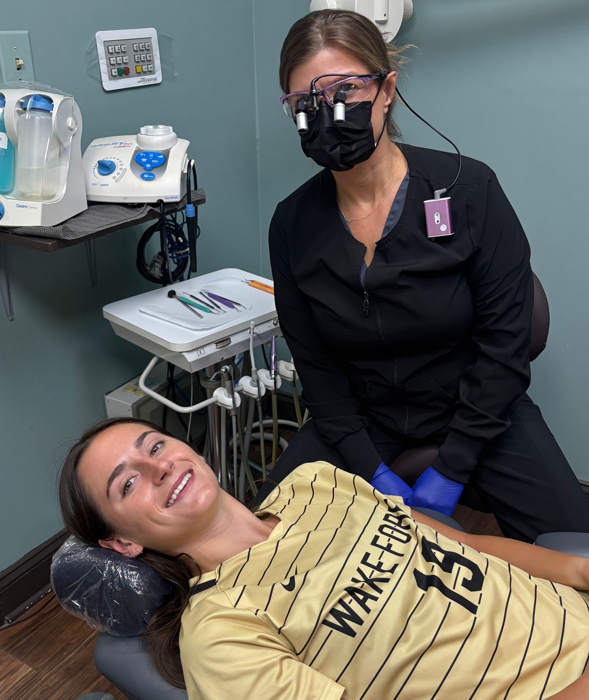 A woman in a wake forest shirt is laying in a dental chair
