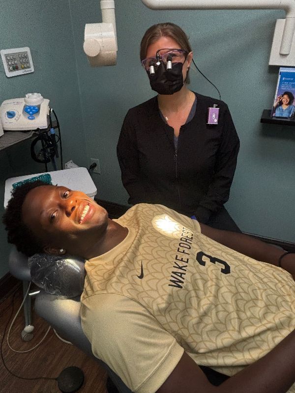 A man in a wake forest jersey is laying in a dental chair