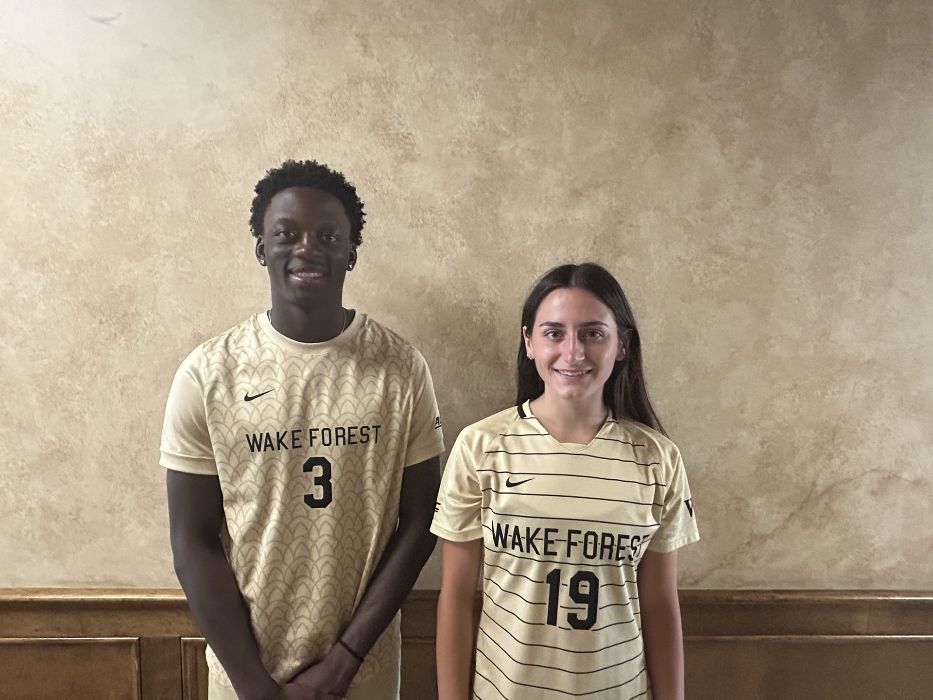 A man and a woman are standing next to each other in front of a wall.