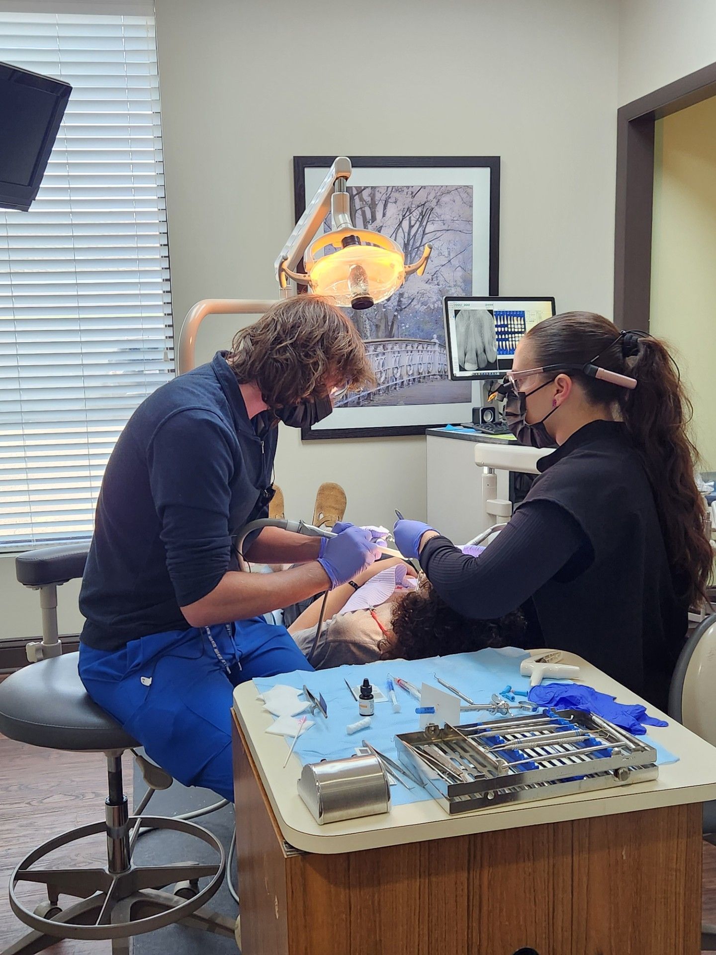 Dentist and assistant treating a patient's teeth in a dental office.