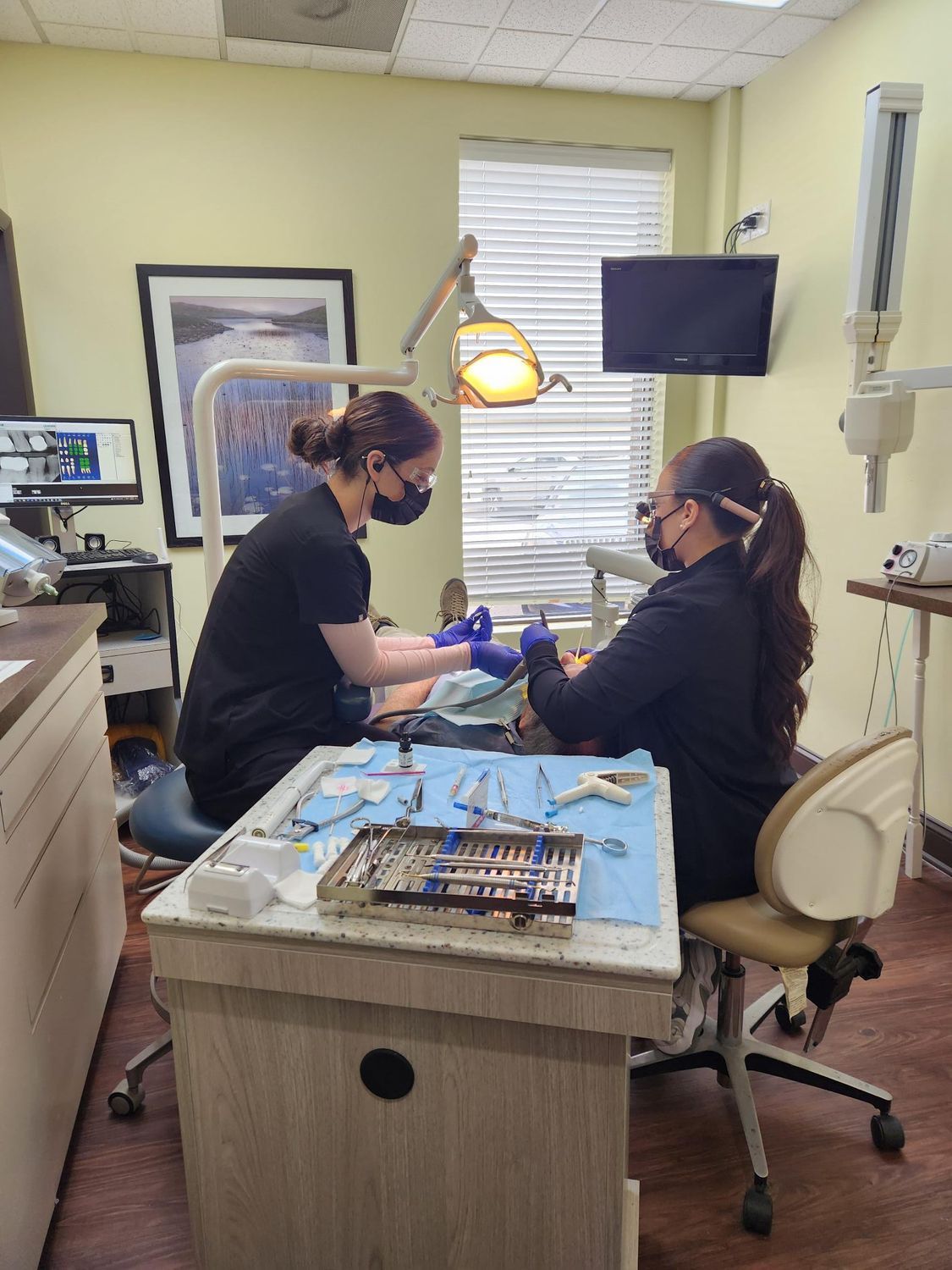 Dos profesionales dentales en una clínica, realizando un procedimiento a un paciente.