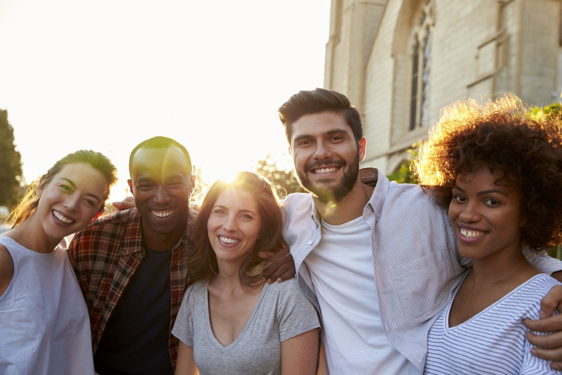 A group of young people are posing for a picture in front of a church.
