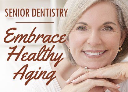 An older woman is smiling with her hands on her face.