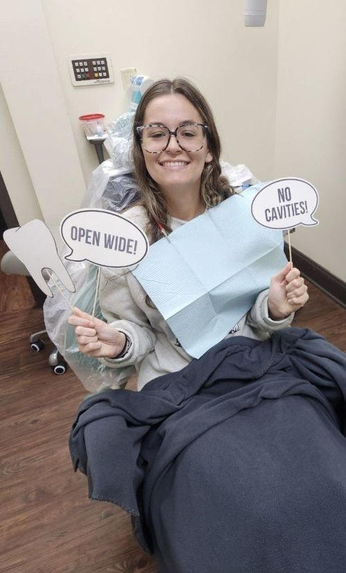Mujer en el dentista sosteniendo carteles que dicen 