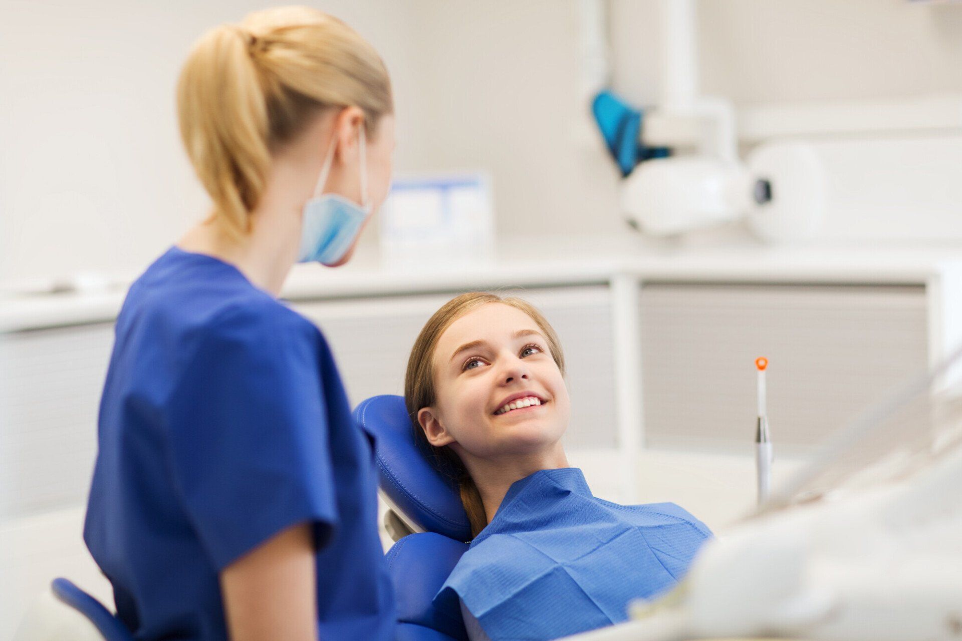 A woman is sitting in a dental chair talking to a dentist.