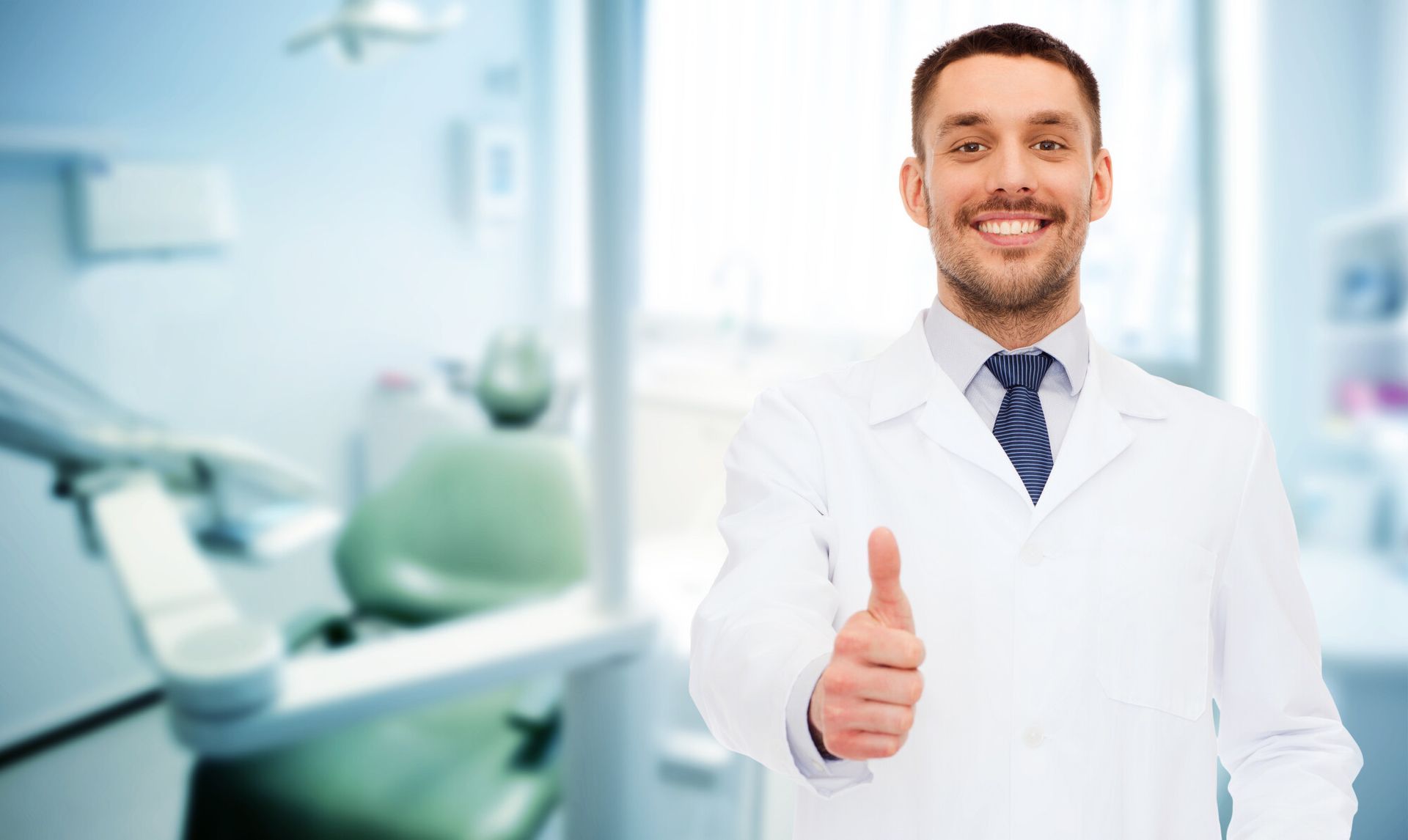 A dentist is giving a thumbs up in a dental office.