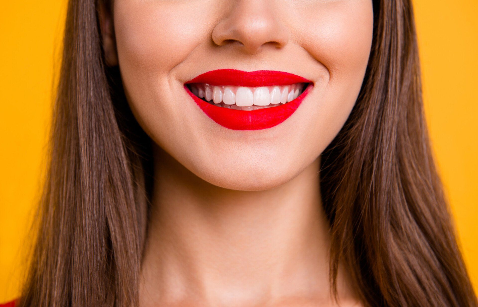 A close up of a woman 's face with red lipstick and white teeth.