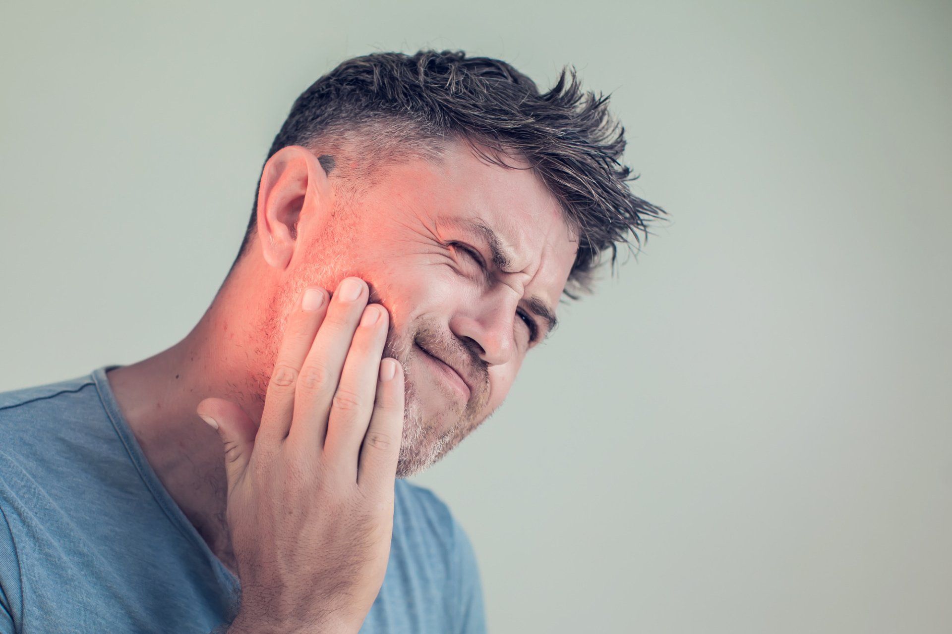 A man is holding his face in pain because of a toothache.