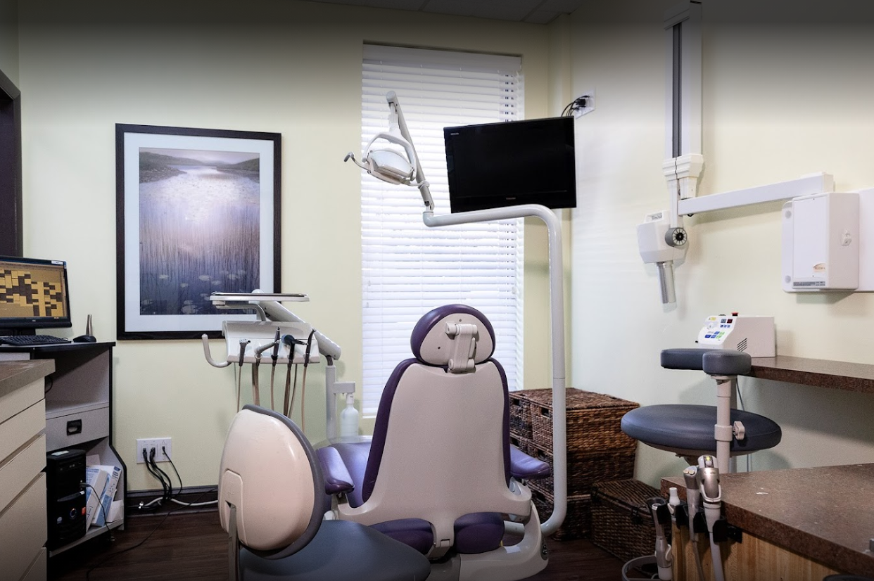 A dental office with a purple chair and a television.