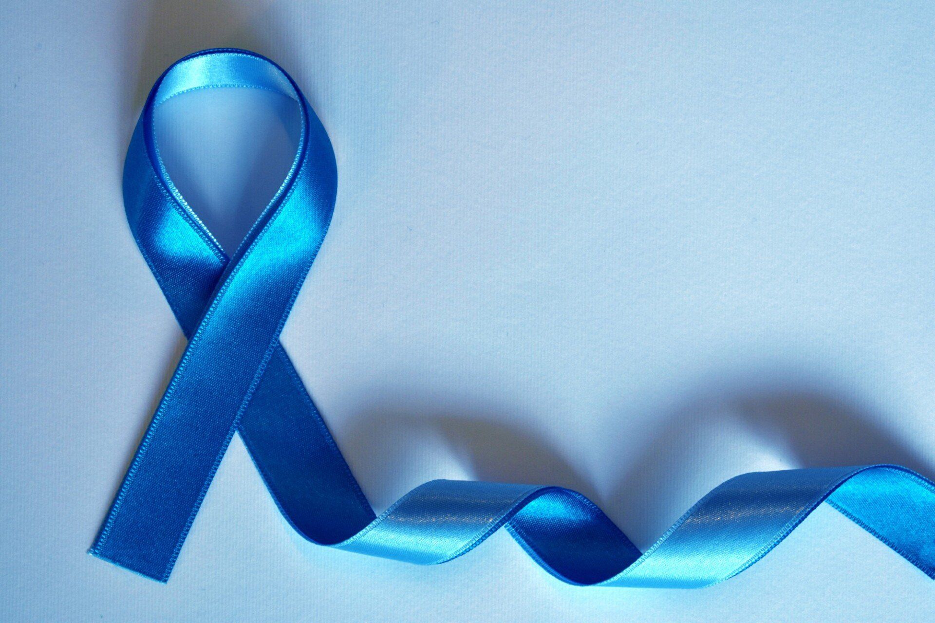 A blue ribbon is laying on a white surface.